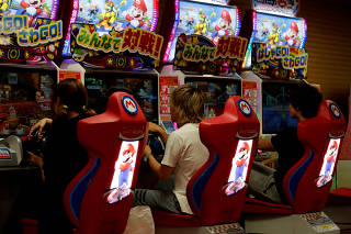 People play Mario Kart Arcade GP DX game at Tatio's game center in Tokyo
