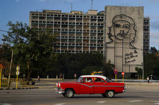 FILE PHOTO: A vintage American car passes beneath a mural of Che Guevara in Revolution Square in Havana