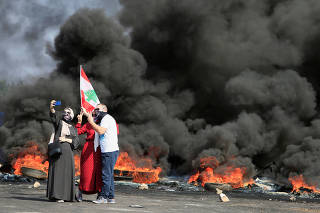 Demonstrators take a selfie in front of burning tires during a protest targeting the government over an economic crisis, at Barja