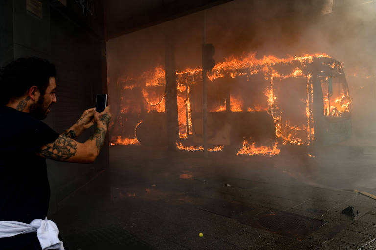 Homem fotografa ônibus em chamas em protesto na capital chilena