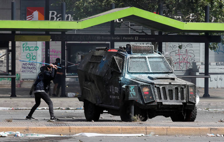 Manifestante usa um bastão para atacar veículo militar em Santiago