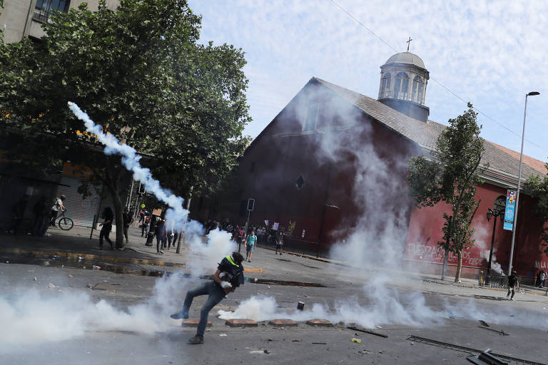 Manifestante joga lata de gás lacrimogêneo durante protesto em Santiago