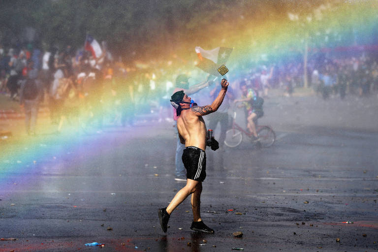 Um arco-íris é visto enquanto manifestantes protestam contra o modelo econômico do estado do Chile em Santiago, Chile