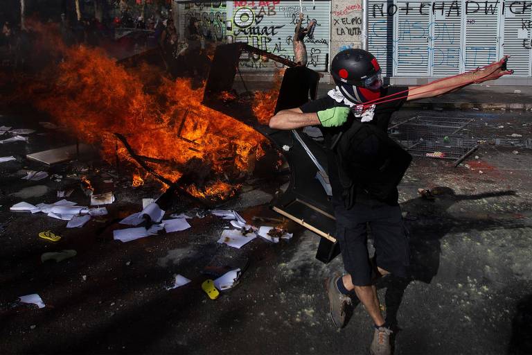 Manifestante usa um estilingue durante os confrontos com a polícia em Santiago, no Chile