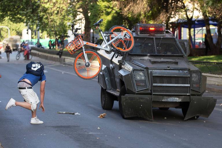Manifestante joga bicicleta me carro da polícia chilena em Santiago, no Chile