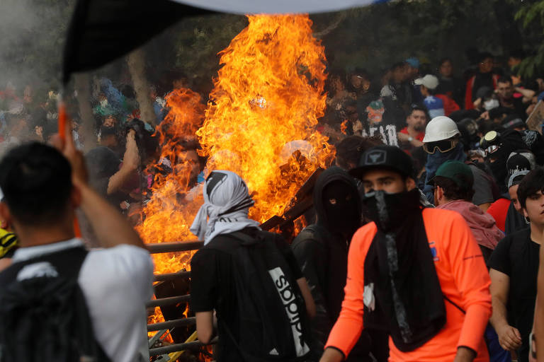 Manifestantes em frente a estação bloqueada por fogo em Santiago