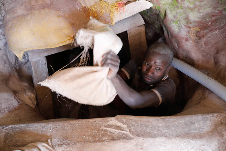 Trabalhador na entrada de túnel em mina de coltan