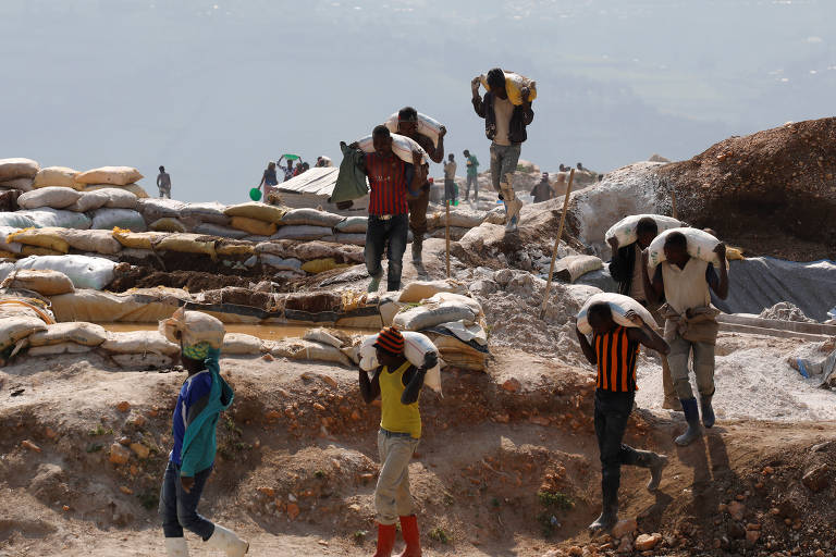 Homens carregam sacos de terra misturados a minério em Rubaya
