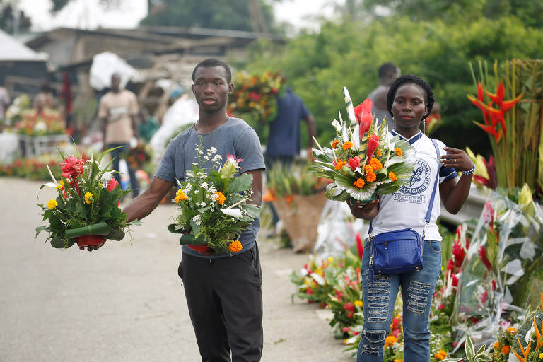 Marfinenses vendem flores em frente ao cemitério de Williamsville durante o Dia de Todos os Santos, em Abidjan, na Costa do Marfim
