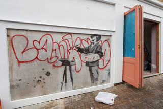 A man walks near a Banksy mural known as The Painter, which first appeared in 2008, before it is officially unveiled in Notting Hill