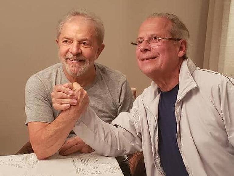 Lula e Dirceu sentados, de mãos dadas sobre a mesa