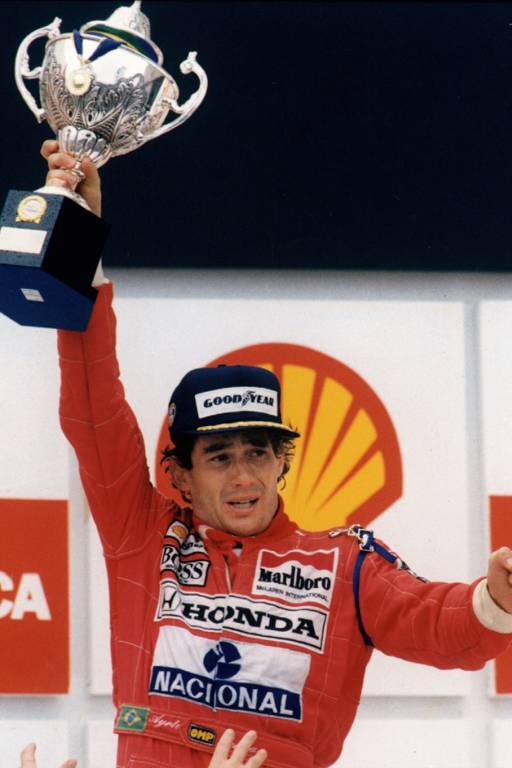 O piloto brasileiro Ayrton Senna traz ainda a expressão de sofrimento no rosto ao receber o troféu do Grande Prêmio Brasil, em 1991, no autódromo de Interlagos. É sua primeira vitória no Brasil. Nas últimas sete voltas, o piloto teve o câmbio de seu McLaren quebrado e usou apenas a sexta marcha