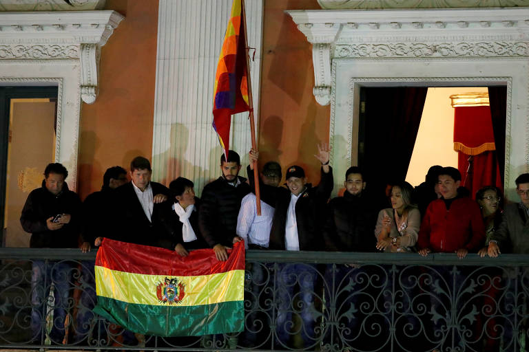 O líder opositor Luis Fernando Camacho segura bandeira que representa todos os povos bolivianos no momento em que a senadora Jeanine Añez se declara presidente da Bolívia, em La Paz