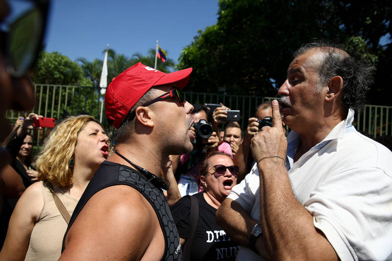 Apoiador de Guaidó (alto, de bigode e camisa branca) discute com militante defensor de Maduro, que usa bone vermelho