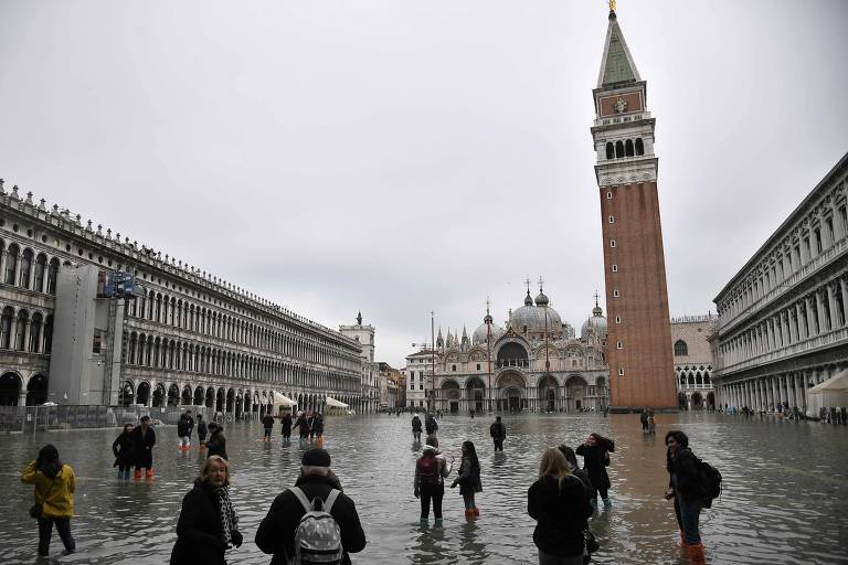 Pessoas caminham na praça de São Marcos, em Veneza, inundada deico ao aumento do nível da água