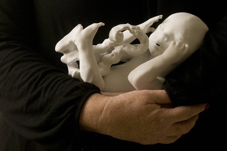 mãos seguram impressão 3D de um feto
