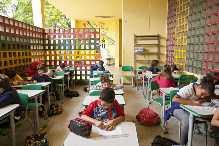 Estudantes em atividade de desenho em sala com as paredes vazadas da Escola Municipal Amorim Lima