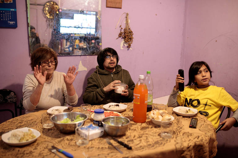 Maria Luz Navarrete Alarcón, 70, faz heiki sobre a comida antes do almoço, ao lado de seu filho Benjamín e sua neta, Esperanza