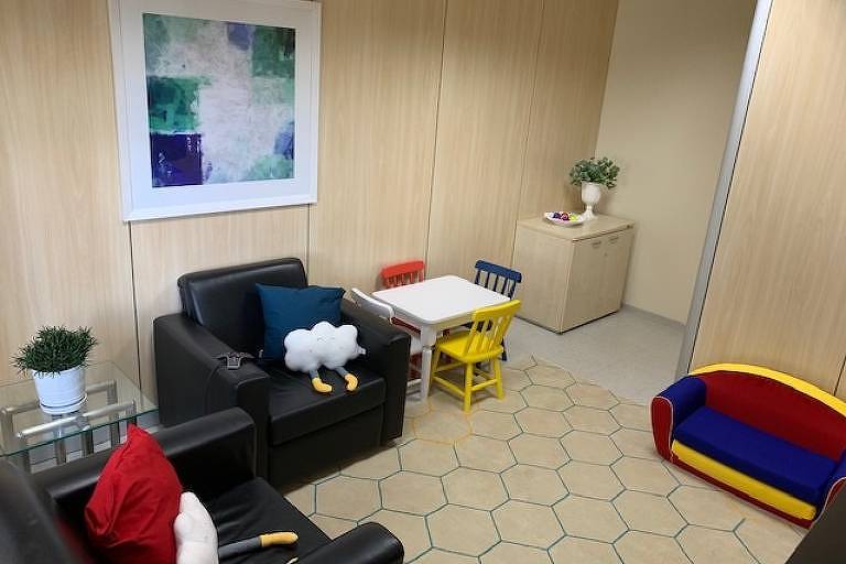 Móveis infantis dispostos em uma sala com poltronas pretas e um sofá todo colorido