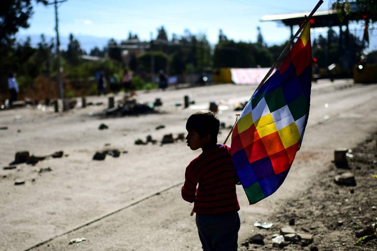 Menino segura bandeira da wiphala, que representa os povos nativos andinos, em uma rodovia bloqueada por manifestantes em Chapare, na Bolívia