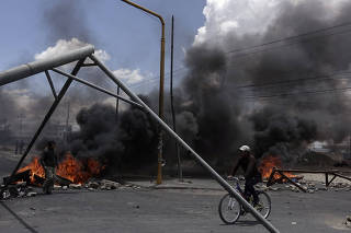 A cyclist rides next to a blocked petrol plant of Senkata in El Alto outskirts of La Paz
