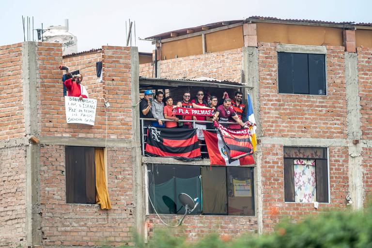 Torcedores do Flamengo assistem ao treino da equipe de uma casa nos arredores do CT da seleção do Peru, em Lima