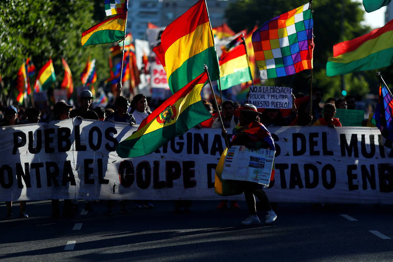 Apoiadores de Evo balançam bandeiras verde, amarela e vermelha da Bolívia e as bandeiras coloridas 