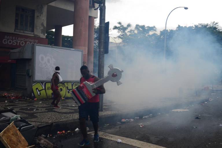 Homem com réplica da Libertadores caminha em rua após a polícia utilizar bombas de efeito moral