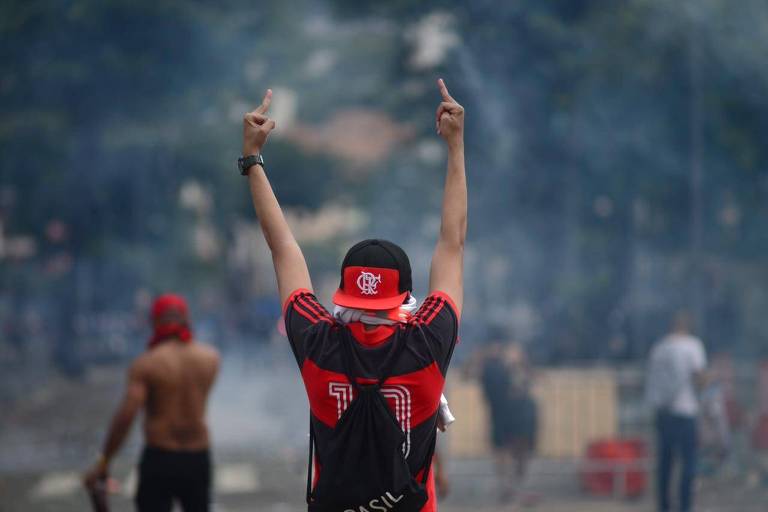 Torcedor faz gesto obsceno para a polícia durante confusão pelas ruas do centro do Rio