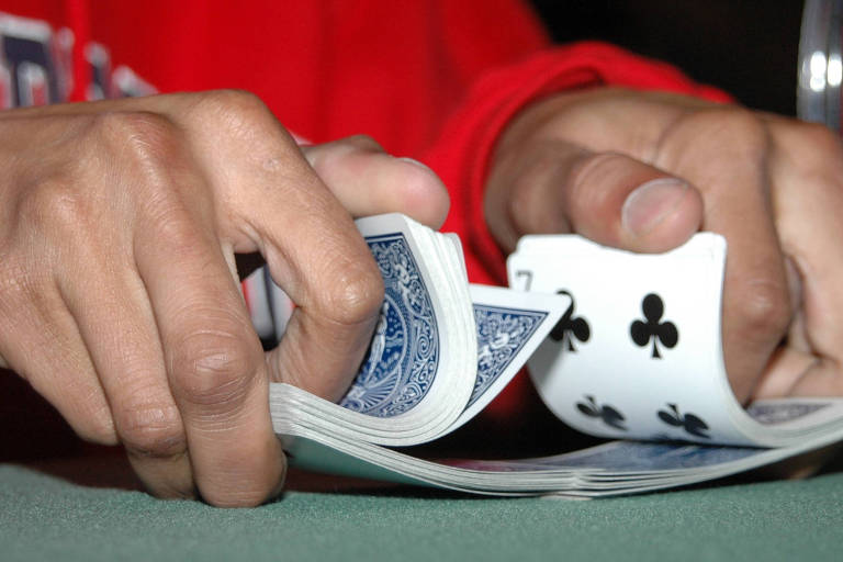 Imagem mostra duas mãos embaralhando um maço de cartas