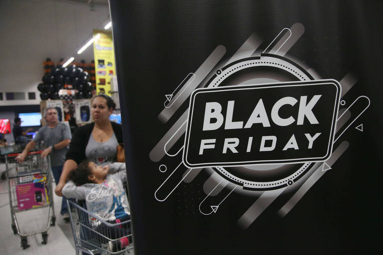 Foto está divida em duas: no canto direito um homem e uma mulher empurram carrinhos de supermercado com mercadorias; no canto esquerdo está um cartar escrito 'Black Friday' em preto