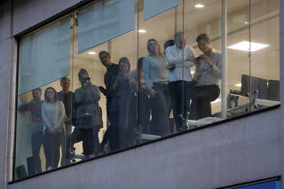 Office workers look through a window near the site of an incident at London Bridge in London