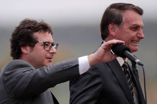Chief of the Secretariat of Social Communication Fabio Wajngarten, mutes the microphone for Brazil's President Jair Bolsonaro, during a Flag Day ceremony at the Alvorada Palace, in Brasilia