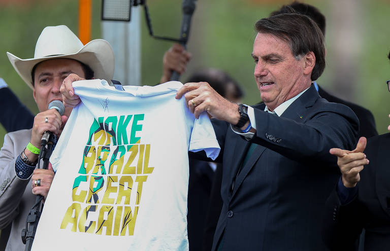Bolsonaro segura uma camisa em que se lê "Make Brazil great again", imitação do slogan de Donald Trump, que significa "tornar o brasil grande novamente"