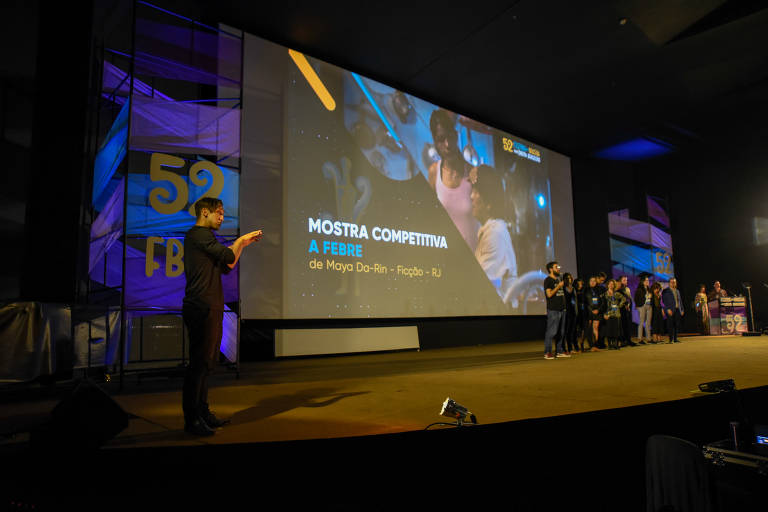 Equipe do filme A Febre no palco do Festival de Brasília, em novembro. O evento teve protestos contra as políticas para cultura do governo Bolsonaro. Em seu primeiro ano de mandaro, o presidente afirmou que a sede da Ancine seria transferida para Brasília em 2020 e cortou 43% do fundo do audiovisual, menor dotação nominal desde 2012