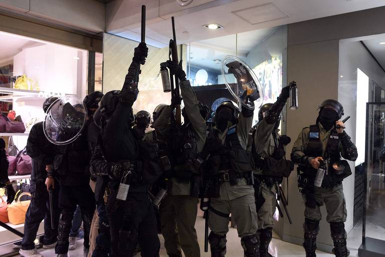 Policiais apontam spray de pimenta enquanto pessoas jogam objetos de cima dentro de shopping de Hong Kong 