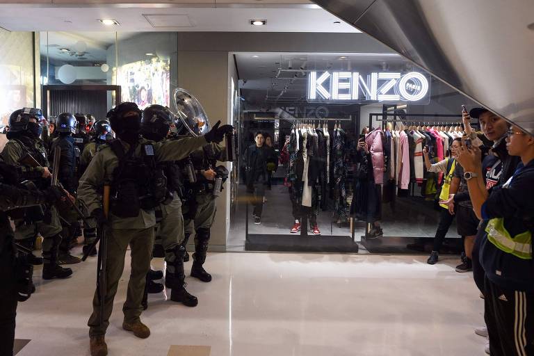 Polícia monta guarda dentro do shopping New Town Plaza, em Hong Kong, enquanto consumidores observam