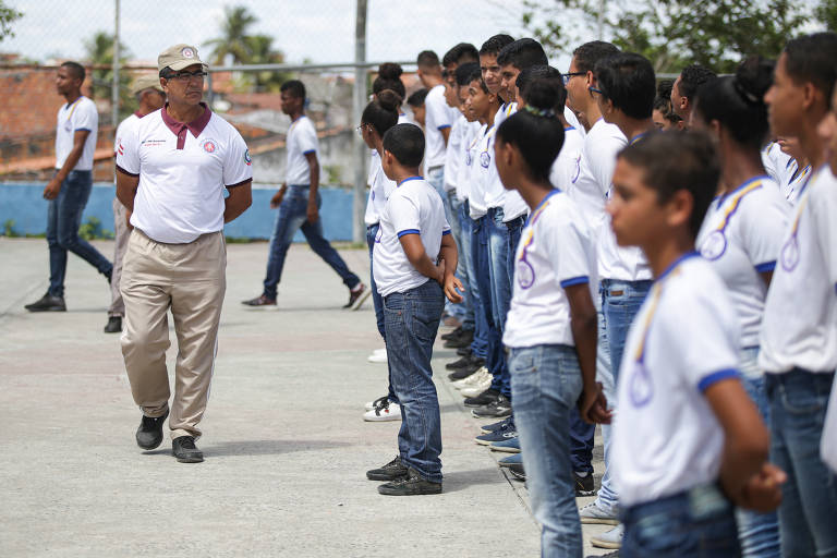 Militar confere a postura dos alunos enfileirados para o hino nacional na escola Ivete Oliveira