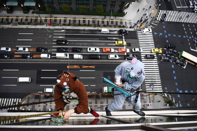 Trabalhadores fantasiados limpam janelas de prédios em Tóquio, no Japão
