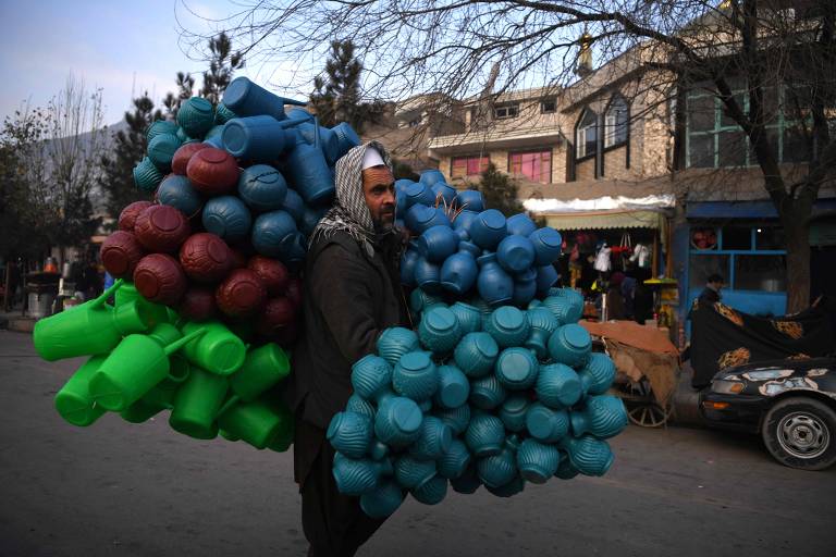 Homem carrega potes de plástico em rua de Cabul, no Afeganistão