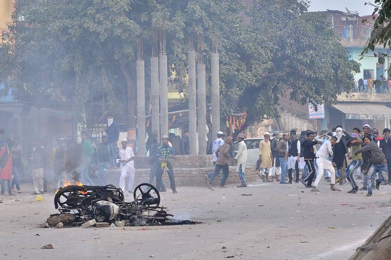 Após moto ser incendiada, manifestantes jogam pedras em policiais durante protesto na cidade de Kanpur, no estado de Uttar Pradesh