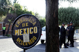 Police officers stand guard next to Mexico's embassy in La Paz