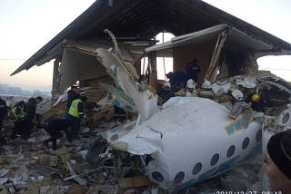 Emergency and security personnel are seen at the site of the plane crash near Almaty