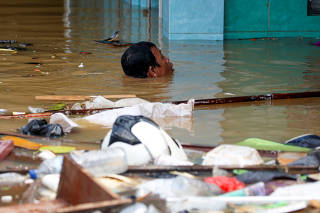 A man swims at a flooded area after heavy rains in Jakarta