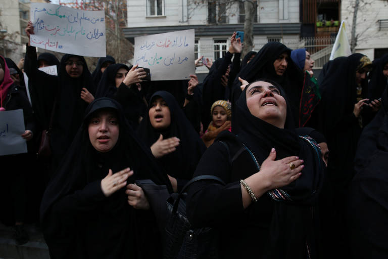 Manifestantes com a mão no peito em frente ao escritório das Nações Unidas em Teerã, em sinal de luto contra o assassinato de Qassim Suleimani
