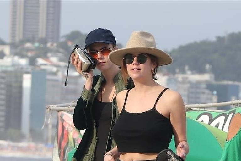 Cara Delevingne e Ashley Benson passeiam entre banhistas na Praia de Copacabana