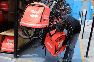FILE PHOTO: A Rappi delivery man picks up his delivery bag, from his bicycle, in Bogota