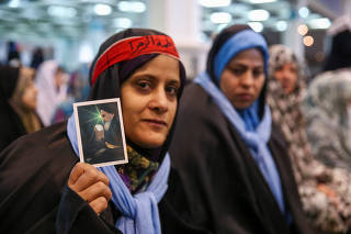 A woman holds the picture of Ayatollah Khomeini during the Friday prayers in Tehran