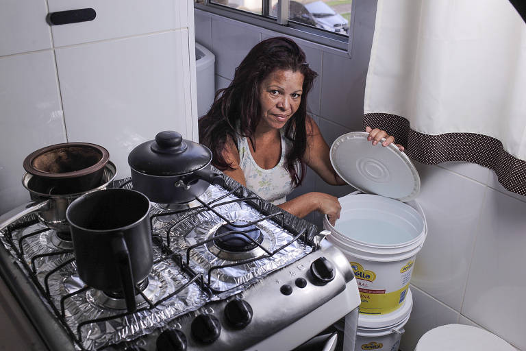 A síndica de condomínio Maria Joana Darc de Andrade, 53 anos, exibe os baldes onde tem guardado água, em Guaianases; moradores reclamam de baixa pressão e falta de água em bairros da zona leste