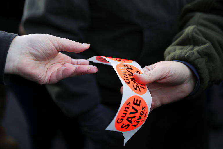 Adesivos com os dizeres "armas salvam vidas" são distribuídos durante a manifestação